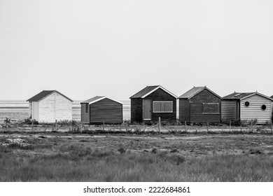 Small wooden Beach Huts in black and white at Seasalter Beach, just outside Whitstable, Kent, UK