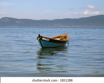 A small wooden boat anchored in a tranquil cove.