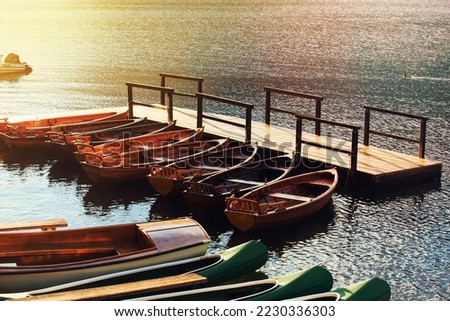 Small wooden boats and canoes docked and tied to empty pier on the lake