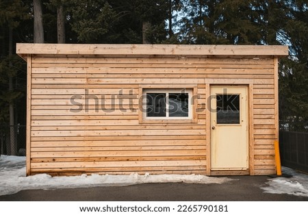 Small wooden cabin house in the evening. Exterior design. Small house for vacation. Log cabin in a forest in the winter. Travel photo, nobody