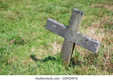 Small Wooden Cross In The Grass Of A Graveyard