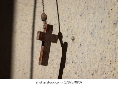 Small Wooden Cross Hanging Against A Wall