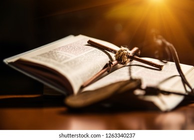 A small wooden cross is lying on the open Bible on a dark background. The cross is tied with a rope. The concept of faith, hope and love - Shutterstock ID 1263340237