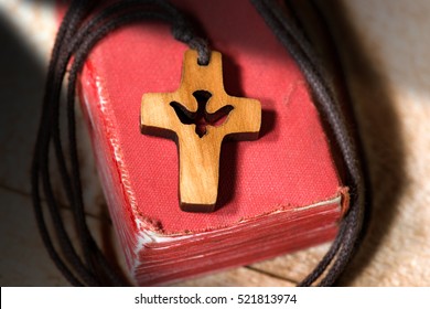 Small wooden crucifix with a dove and rope on an old Holy Bible