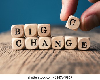 Small wooden dices with the word Change on an office table, hand puts the c on it