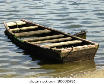 A Small Wooden Dinghy On The Beach Sand