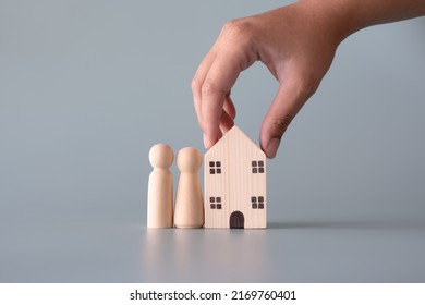 Small wooden faceless figures of human family members and house. Property, hospitality, orphanage concept using wooden house and human model.