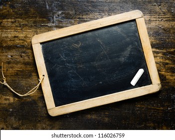 Small wooden framed blank blackboard with a piece chalk on a darl timber background with woodgrain suitable for your greeting, message or menu - Powered by Shutterstock