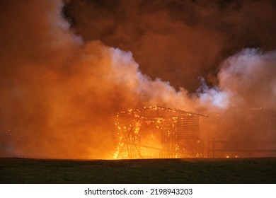 A Small Wooden House Burning At Night, Sparks Fly In The Sky