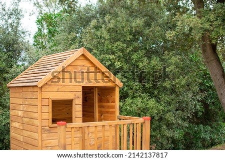 Small wooden house for children in the woods. Playground surrounded by trees. 