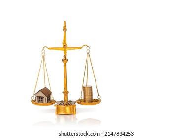 Small wooden house and stacked golden coins on weighing scales isolated on white background. Mortgage and real estate investment concept. Copy space.