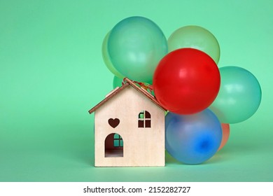 Small Wooden Model House With Balloons Tied To The Roof. Party House Concept.