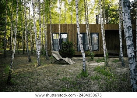 Small wooden modern house with big windows in the birch forest