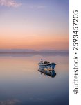 Small wooden rowing boat on a calm lake at sunset reed in France