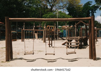 A small wooden swingset on a sandy playground