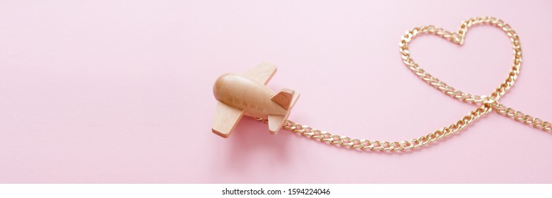 Small Wooden Toy Airplane Carries In The Shape Of A Heart From A Gold Chain