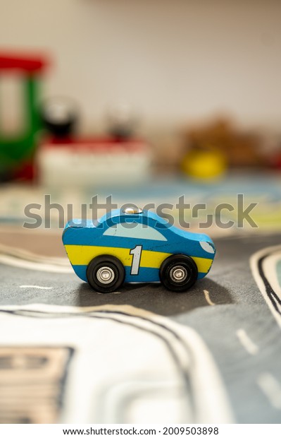 Small wooden toy car with painted number one on a\
playground carpet 