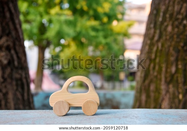 A small wooden toy\
car. Tree background.