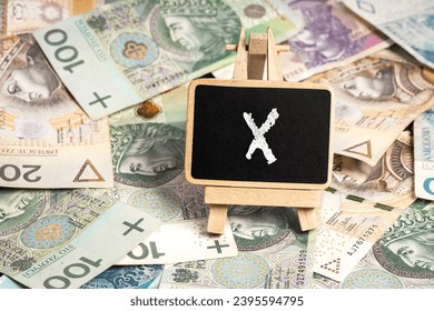 a small wooden writing board standing on scattered Polish zloty PLN banknotes, a chalk inscription 