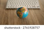 Small world globe in front of a computer keyboard representing global technology