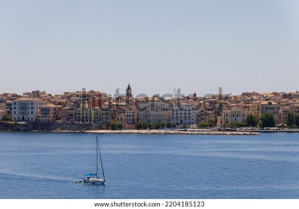 Small yacht with assembled sails
against the backdrop of the front facades of the embankment of
Corfu city on a clear summer day, Ionian islands,
Greece