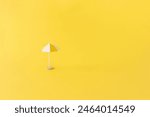 small yellow beach umbrella on yellow background wit copy space