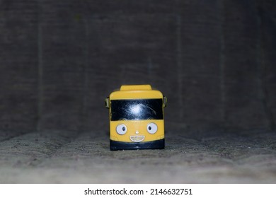 A Small Yellow Bus Toy Seen From The Front From An Eye Level Perspective