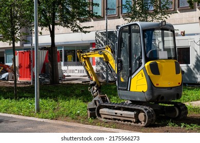 A Small Yellow Excavator At A Construction Site In The City. Quiet Deserted Street.