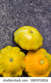 Small Yellow Squash On A Grey Blurred Background, Close Up. Autumn Harvest Of Vegetables. Copy Space. Baby Pattypan Squash (Cucurbita Pepo)