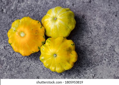 Small Yellow Squash On A Grey Blurred Background, Close Up. Autumn Harvest Of Vegetables. Copy Space. Baby Pattypan Squash (Cucurbita Pepo)