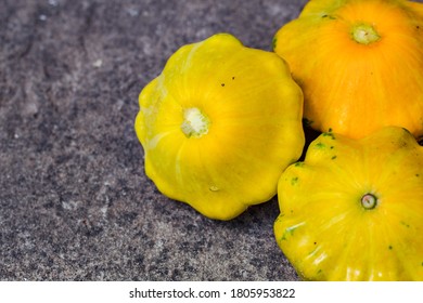 Small Yellow Squash On A Grey Blurred Background, Close Up. Autumn Harvest Of Vegetables. Copy Space. Baby Pattypan Squash (Cucurbita Pepo)