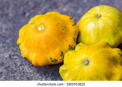 Small Yellow Squash On A Grey Blurred Background, Close Up. Autumn Harvest Of Vegetables. Copy Space. Baby Pattypan Squash (Cucurbita Pepo)