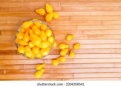 Small Yellow Tomatoes In A Glass Bowl. Closeup Image Of Yellow Pear Tomatoes. View From Above. Organic Healthy Food.