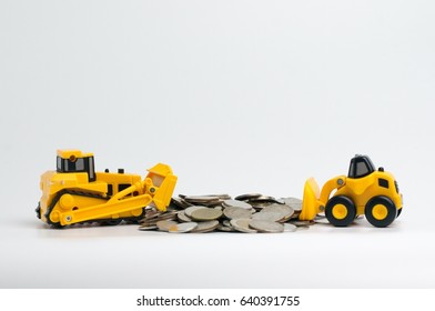 Small yellow toy excavator and bulldozer with coins isolated on white background.