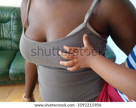 Small young toddlers hand on  sister's breast 