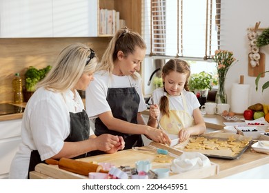 Smalla Adorable Girl Trying To Whisk Eggs In Bowl. Older Sister And Elderly Mother Teaching Schooler Daughter Baking Cookies Biscuits.