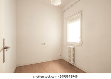 A smaller room featuring a single window with a radiator beneath it, plain white walls, and minimalistic design creating a simple and clean atmosphere. - Powered by Shutterstock