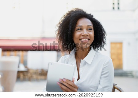 Smart afro student looks smiling. Prints a message in the messenger to the client by mail. A confident woman works outside the home.