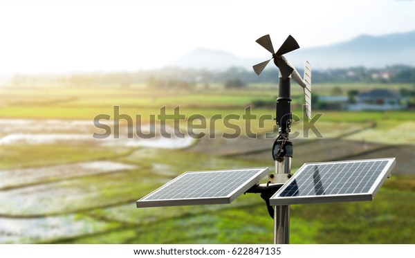 Smart agriculture and smart farm technology\
concept. Revolving vane anemometer, a meteorological instrument\
used to measure the wind speed and solar cell system with rice\
field background.