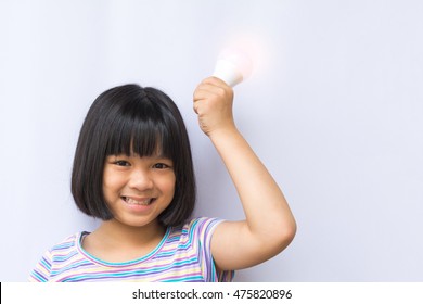 Smart Asia Kid Hold LED Bulb In Her Hand. Happy Smiley Asian Girl Child Having An Idea Concept On White Background.Positive Thinking .Child Safety And Protection Month. World Thinking Day