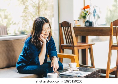 Smart asian business women talking phone sitting on sofa in cafe