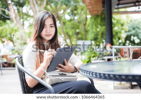 Smart asian business women use tablet sitting in coffee shop outdoor