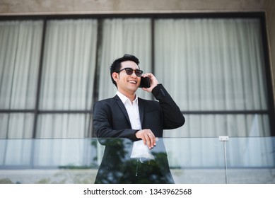 Smart Asian Businessman Talking With Phone With Building Background, Lifestyle Concept.