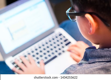 Smart Asian Preteen Boy With Blue Light Blocking Glasses Is Online Learning With His Laptop. Technology And Learning Concept. E-learning, Coding, Programing, Online, Social Media, Computer Device.