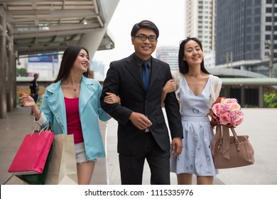 Smart Asian senior businessman dating and shopping with two beautiful Chinese girls. Rich happy man with cute women in city. Threesome by money concept.