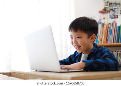 Smart and attractive Asian boy looking at the laptop, video call with someone. Family enjoy distant talk by video call, spend time on internet, online education concept.