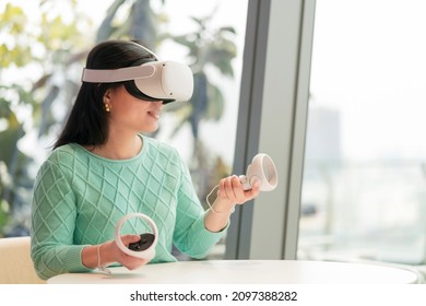 smart attractive asian female business owner weared virtual reality augmented reality glasses enjoys casual metaverse meeting with concentrate at cafe,asian female wear headset goggle gear in cafe - Powered by Shutterstock