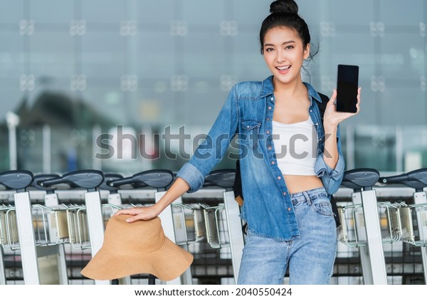 smart attractive asian female hand hold\
smartphone checking for taxi schedule on application screen smart\
city travel ideas concept,asian female use smartphone call taxi at\
terminal platform station