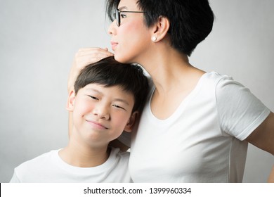 A Smart And Beautiful Asian Mom Holding Her Preteen Son With Love. Her Son Leans His Head On Her Chest Smiling Happily. Love Expression, Parenting Teen, Single Mom, Young Son, Mommy's Love Concept.