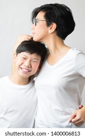 A Smart And Beautiful Asian Mom Holding Her Preteen Son With Love. Her Son Leans His Head On Her Chest Smiling Happily. Love Expression, Parenting Teen, Single Mom, Young Son, Mommy's Love Concept.